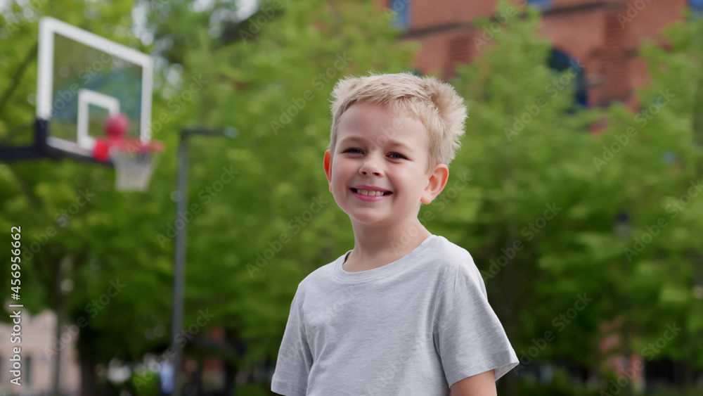 Portrait of cute blonde preschooler boy at basketball playground looking at camera Portrait of cute blonde preschooler boy at basketball playground looking at camera