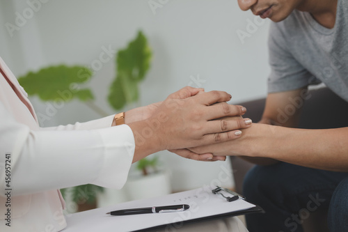 Asian young man  male suffers in mental need to therapy with psychologist while sitting on couch  consult with psychiatrist and encouragement patient by touching  holding to make his feel relaxed.