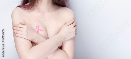World Breast cancer day concept. Woman covers her chest with her hands with painted pink ribbon. October Breast Cancer Awareness month. Copy space