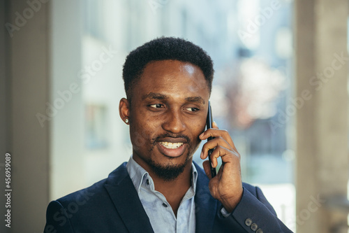 close up portrait of african businessman talking on the phone and smiling from success in business suit