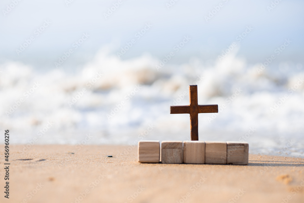 A wooden cross on the sand on the beach.
