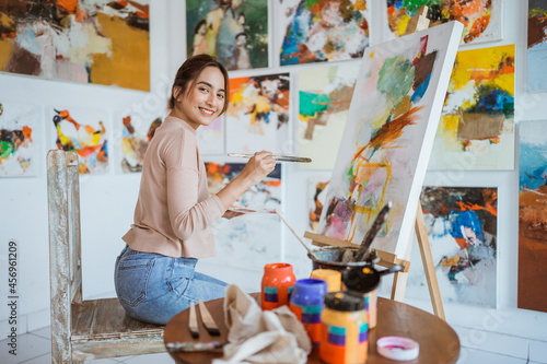 asian female artist painting on canvas doing some art projects on her studio workshop photo
