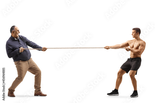 Full length profile shot of a mature man and a strong bodybuilder pulling a rope photo
