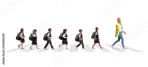 Teacher wearing a safety vest and schoolchildren crossing street behind