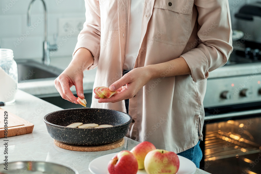 A woman in the kitchen lays out a fresh apple sliced into slices in a baking dish. Cooking. Baking from rice flour A woman in the kitchen lays out a fresh apple sliced into slices in a baking dish. Cooking. Baking from rice flour