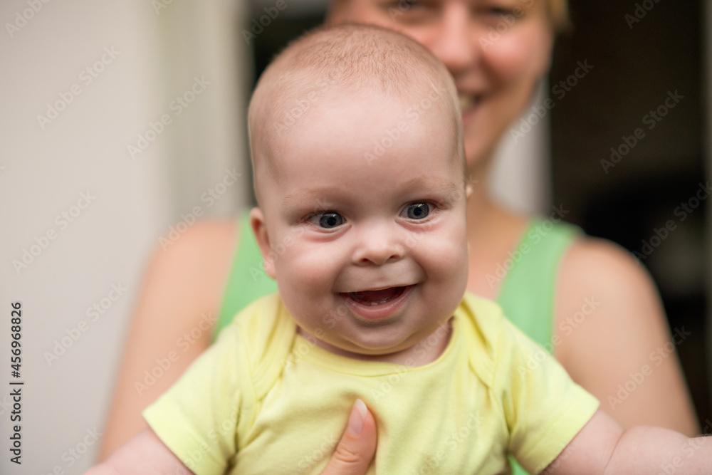 Mother enjoys holding her little cheerful baby boy.