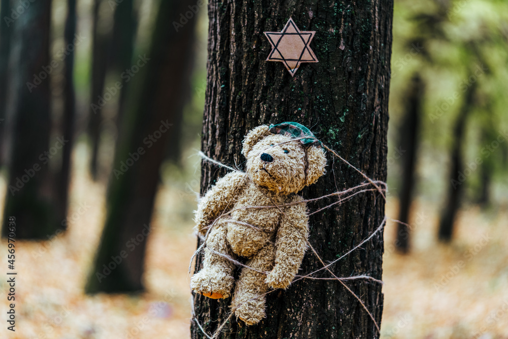 Teddy bear tied to a tree and the star of David above it. Holocaust concept.