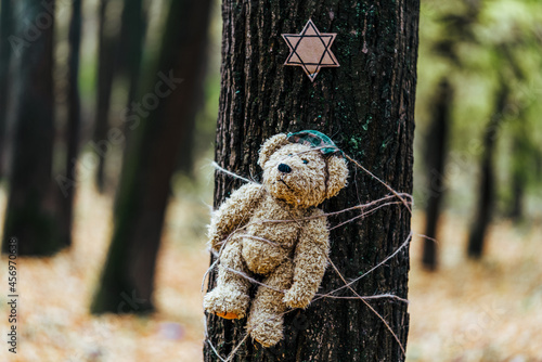 Teddy bear tied to a tree and the star of David above it. Holocaust concept. photo