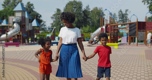 Afro-american mother and two children walking at kids playground