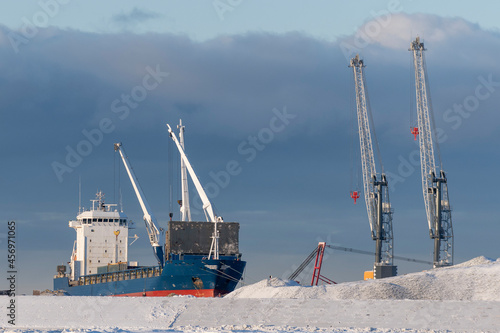 Cargo vessel moored in arctic port. Winter time. Ice navigation. Loading in progress. photo