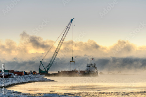 Tug moored to bardge. Strong fog in Arctic sea. Construction Marine offshore works. Dam building, crane, barge, dredger.
