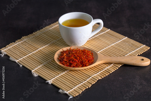 Canvas-taulu Safflower, False Saffron , Saffron Thistle in wooden spoon and a cup of tea