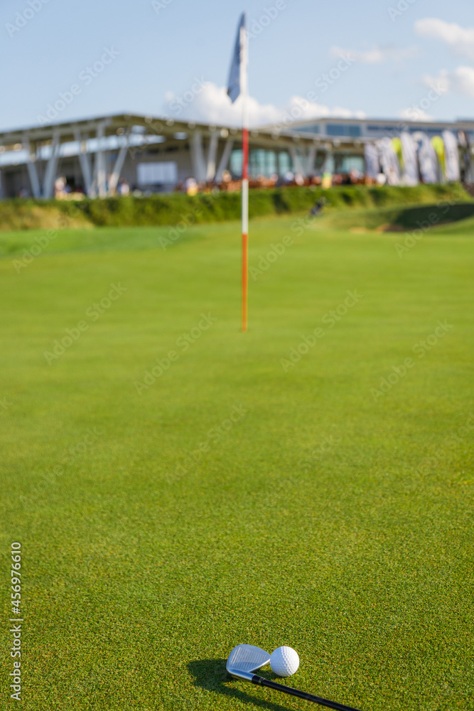 Obraz premium Golf ball and putter on the green grass next to the hole.