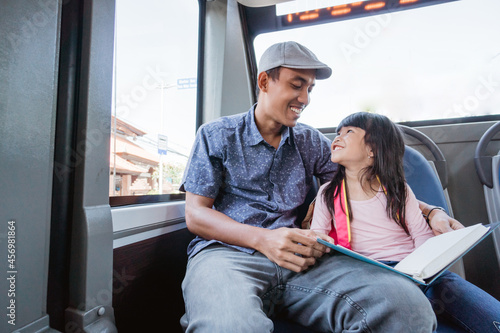 asian father taking his daughter to school by riding bus public transport and studying © Odua Images