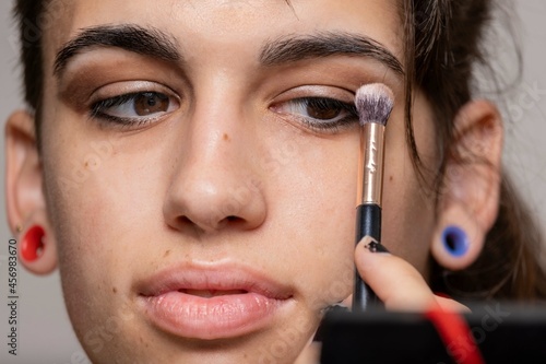 Young transgender woman putting on her eyes. Daily life