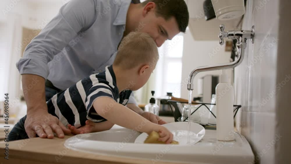 Father with down syndrome son indoors in kitchen, washing dishes. Father with down syndrome son indoors in kitchen, washing dishes.