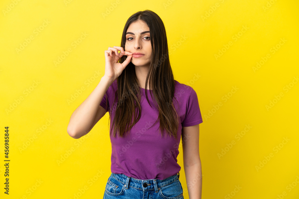 Young caucasian woman isolated on yellow background showing a sign of silence gesture Young caucasian woman isolated on yellow background showing a sign of silence gesture