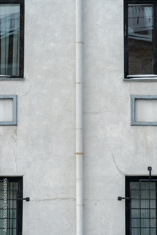 Obraz premium An unusual facade of an office building. Narrow non-standard windows form an amazing recognizable style. A drainpipe spoils the beautiful style of an old building