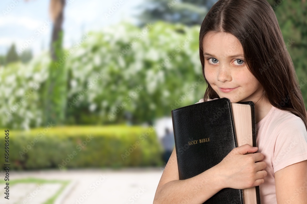 Fototapeta premium smart and nerd kid girl holding Bible for study in church.