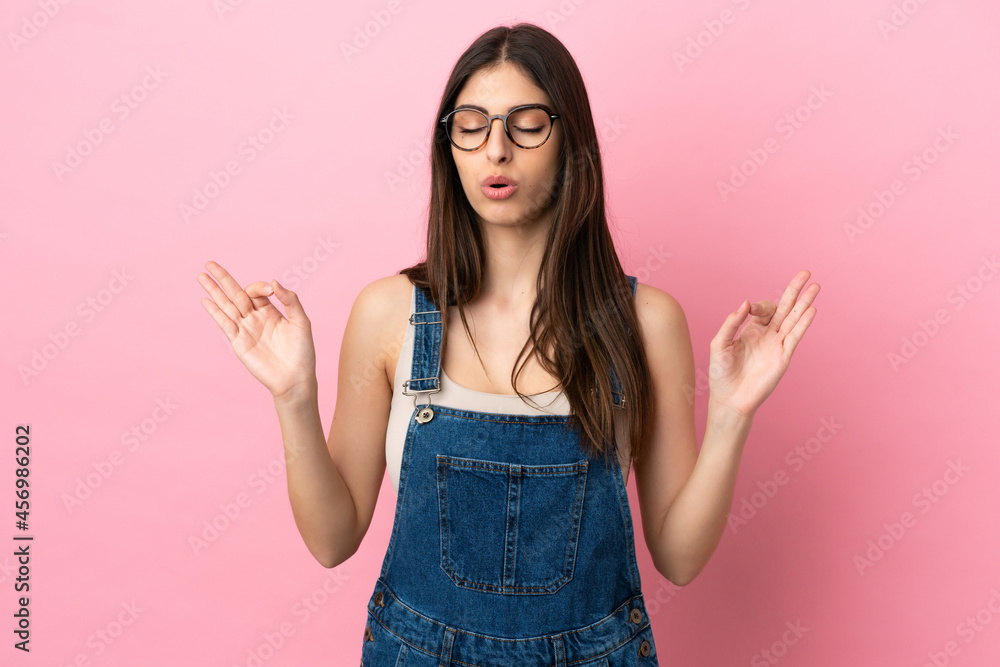 Young caucasian woman isolated on pink background in zen pose Young caucasian woman isolated on pink background in zen pose