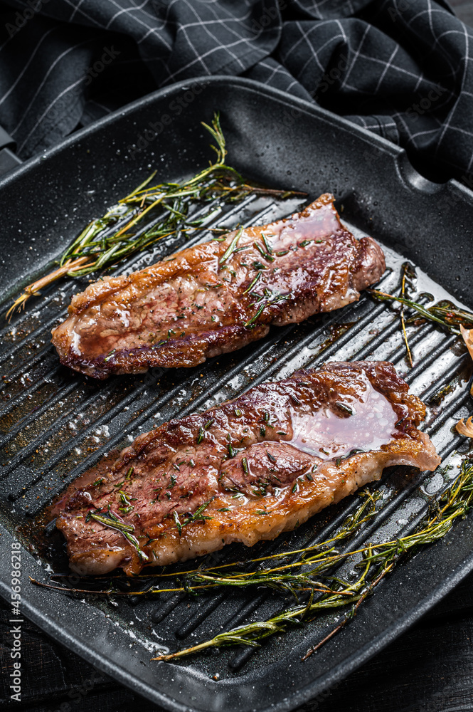 Grilled Prime Black Angus beef steaks Striploin or New York in a grill pan. Dark wooden background. Top view