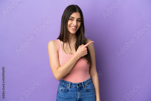 Young caucasian woman isolated on purple background pointing to the side to present a product