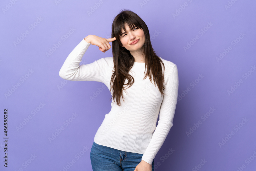 Young Ukrainian woman isolated on purple background making the gesture of madness putting finger on the head Young Ukrainian woman isolated on purple background making the gesture of madness putting finger on the head