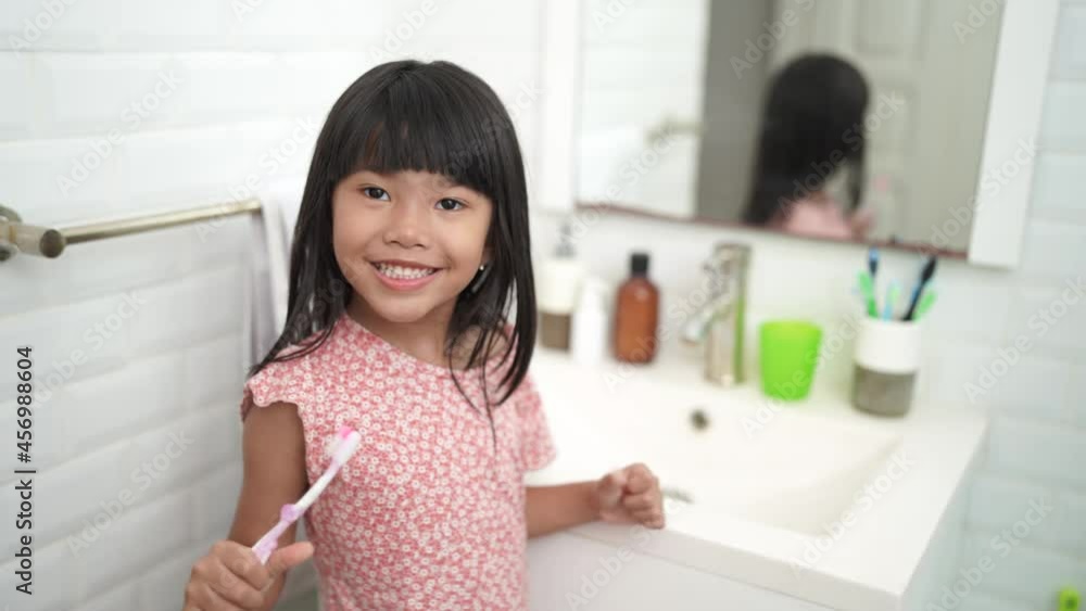 asian little girl brushes her teeth alone in the bathroom asian little girl brushes her teeth alone in the bathroom