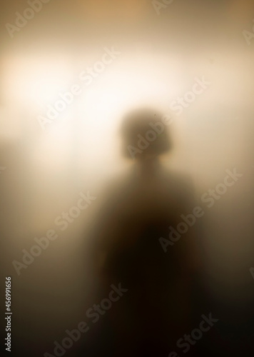 Sihouette of girl highly diffused by warm toned rosted glass