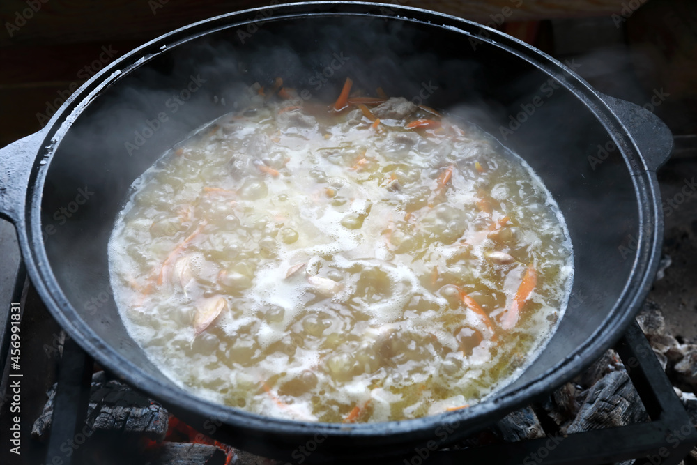 View of cooking pilaf in cauldron on fire View of cooking pilaf in cauldron on fire
