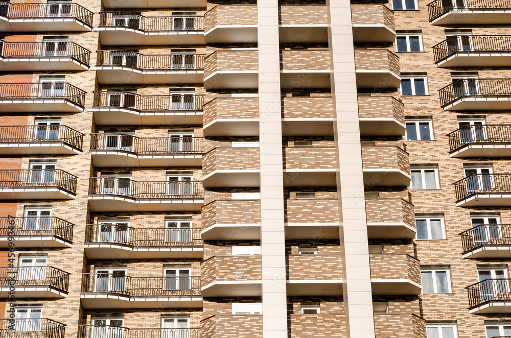 facade of a multi-storey new residential building made of multicolored bricks with wrought-iron and brick balconies. Construction of apartment buildings. facade of a multi-storey new residential building made of multicolored bricks with wrought-iron and brick balconies. Construction of apartment buildings.