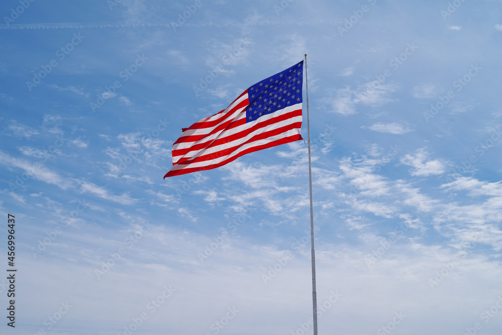Large American flag shown against a blue sky with some clouds in Arizona.