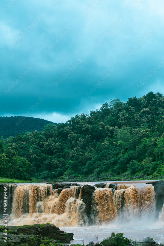 Obraz premium Vertical image of Gira waterfall and lush green mountain at Waghai, Saputara, Gujarat, India. Beautiful natural landscape