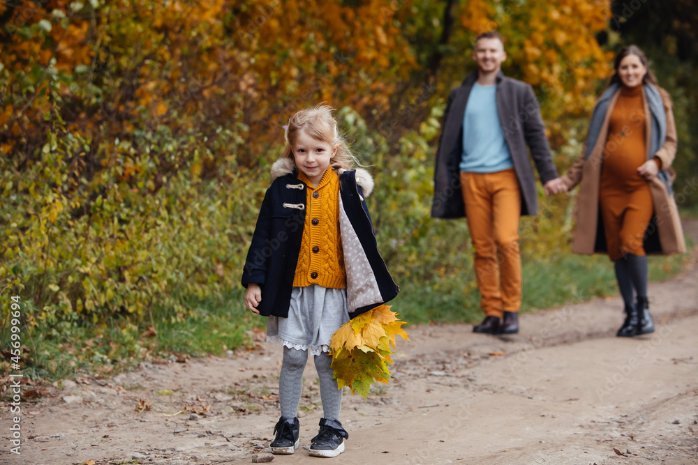 Fototapeta premium father daughter and pregnant mother walking by autumn park