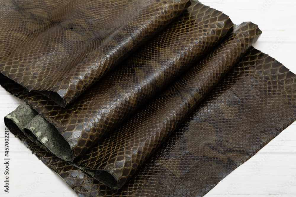 Brown dyed folded natural genuine python leather on the wooden table	
