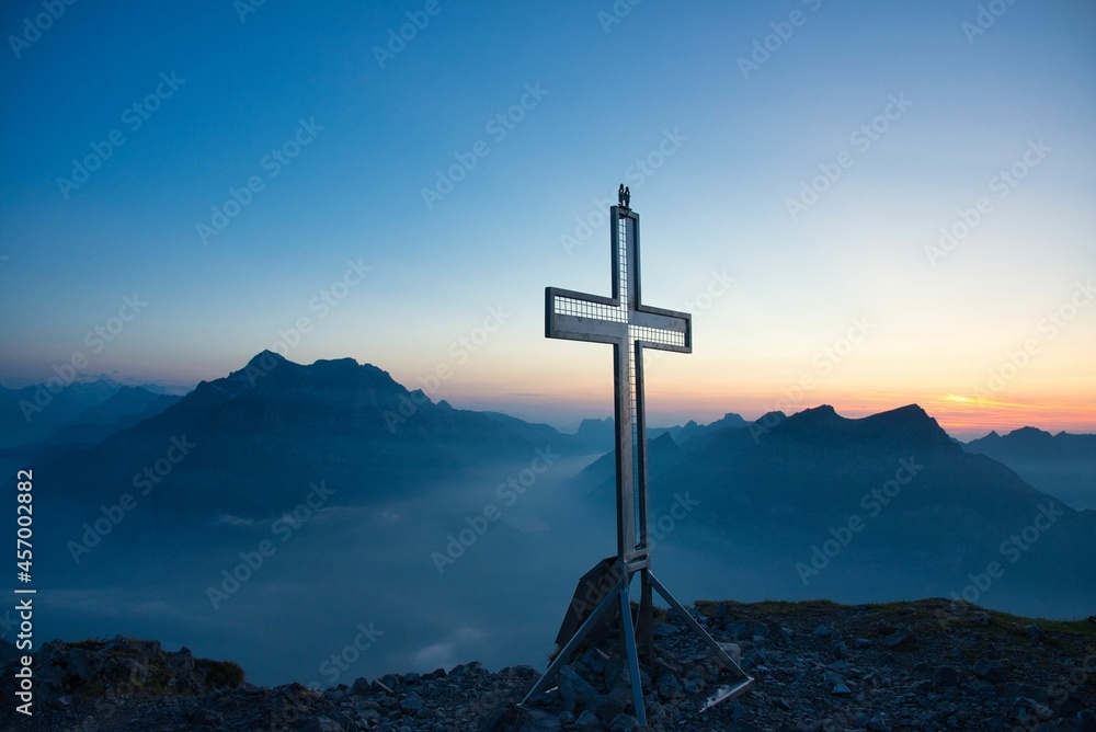 beautiful Stunning sunset with cross on top of mountain peak Switzerland