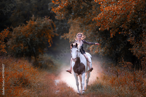 Image of a girl riding a horse in a forest during fall at sunset