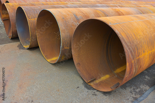Red brown rusty steel pipes in a row with handwritten numbers on it.