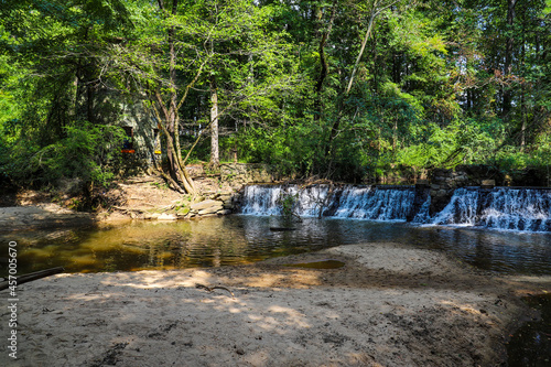 a majestic shot of a waterfall on South Fork Peachtree Creek surrounded by lush green trees reflecting off the water at Lullwater Preserve in Decatur Georgia photo