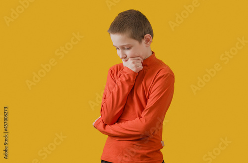 boy in an orange turtleneck stands pensively on a yellow background