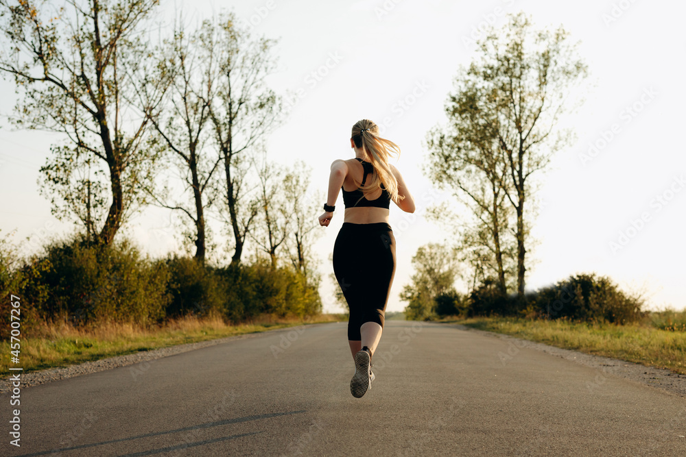 Young sporty girl running on a road at sunset. Lifestyle sports motivation. Young sporty girl running on a road at sunset. Lifestyle sports motivation.