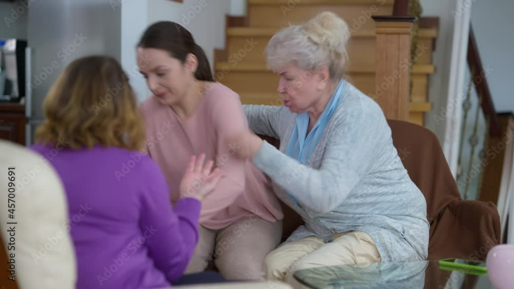 Angry dissatisfied furious grandmother and mother yelling at sad stressed young woman and depressed beautiful millennial leaving passing camera. Conflict of Caucasian multigenerational family at home Angry dissatisfied furious grandmother and mother yelling at sad stressed young woman and depressed beautiful millennial leaving passing camera. Conflict of Caucasian multigenerational family at home