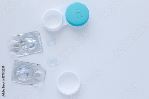 A container for lenses, two sealed lenses and lenses lying on a table on the side on a white background with a place for text. top view, flat lay, copy space, isolate