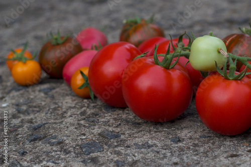 Different ripe tomatoes on the grey stone background.