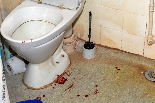 Blood stains on the floor in the bathroom near the toilet