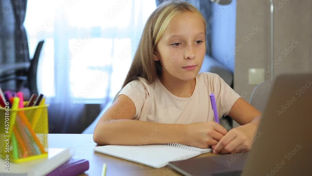 Schoolgirl studies online using a modern laptop. Homework Schoolgirl studies online using a modern laptop. Homework