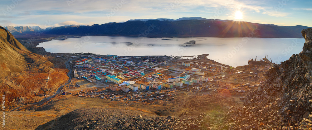 Beautiful morning arctic landscape. Top view of a small port town on the coast of a sea bay among the mountains. Sunrise over the mountains. Egvekinot, Kresta Bay, Chukotka, Siberia, Far North Russia.
