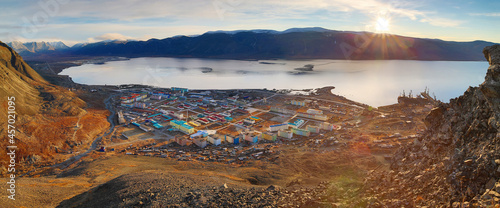 Beautiful morning arctic landscape. Top view of a small port town on the coast of a sea bay among the mountains. Sunrise over the mountains. Egvekinot, Kresta Bay, Chukotka, Siberia, Far North Russia.