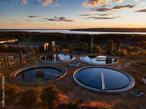 Modern sewage treatment plant. Round wastewater purification tanks at sunset, aerial view