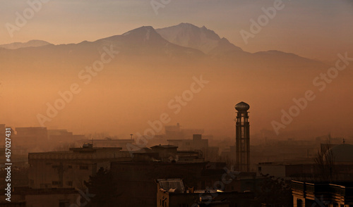Sunrise scene over the city of Kabul in Afghanistan – Mosque tower and mountains – with buildings and infrastructure – misty weather